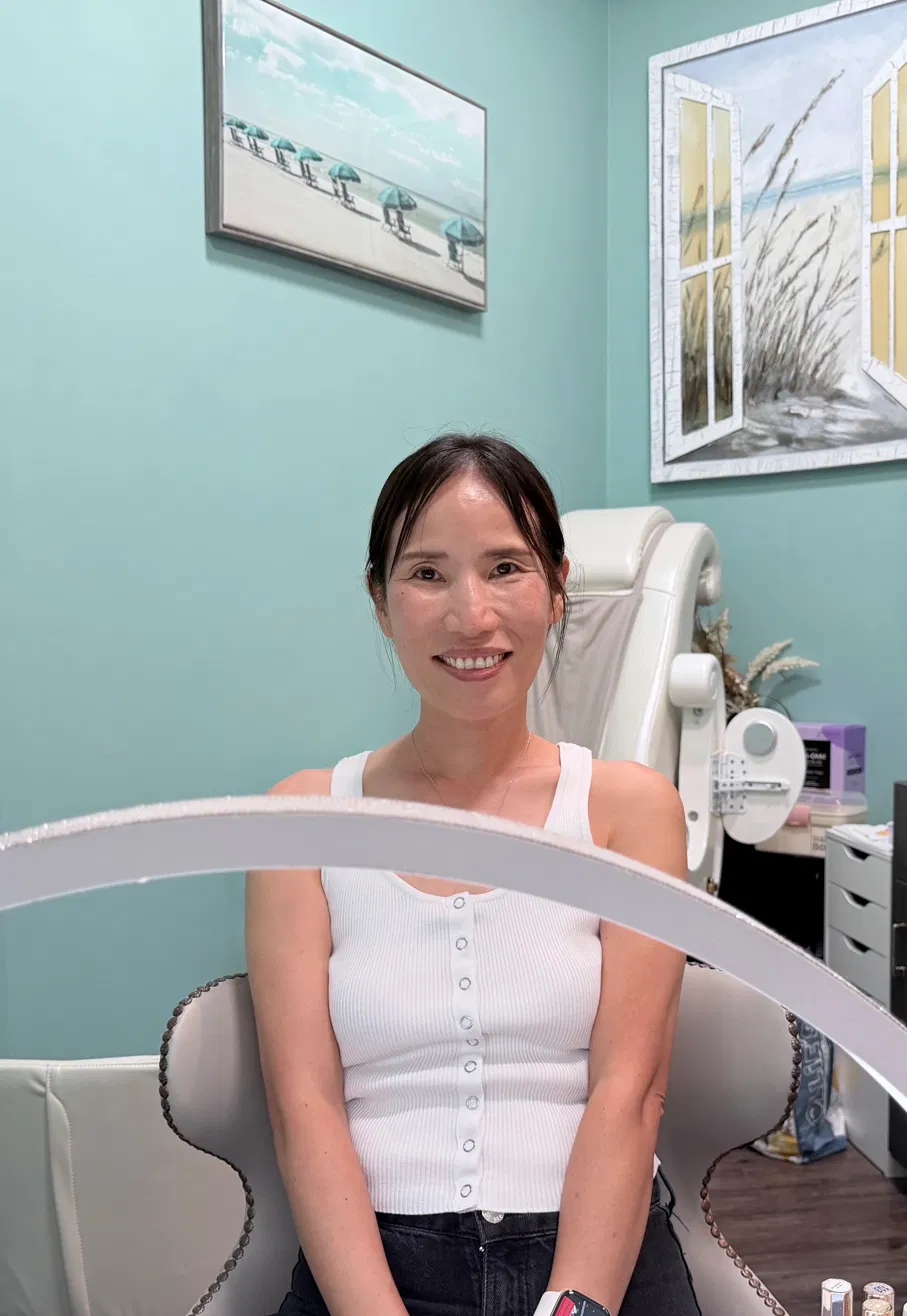 Sun at her nail station with teal walls